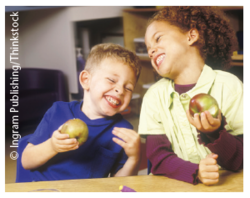 Zwei lachende Kinder mit Apfel in der Hand. © Ingram Publishing/Thinkstock