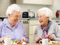 Seniorinnen sitzen am Tisch und essen.