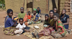 Frauen und Kinder sitzen vor einer Hütte in Malawi. © Stefan Koppmair